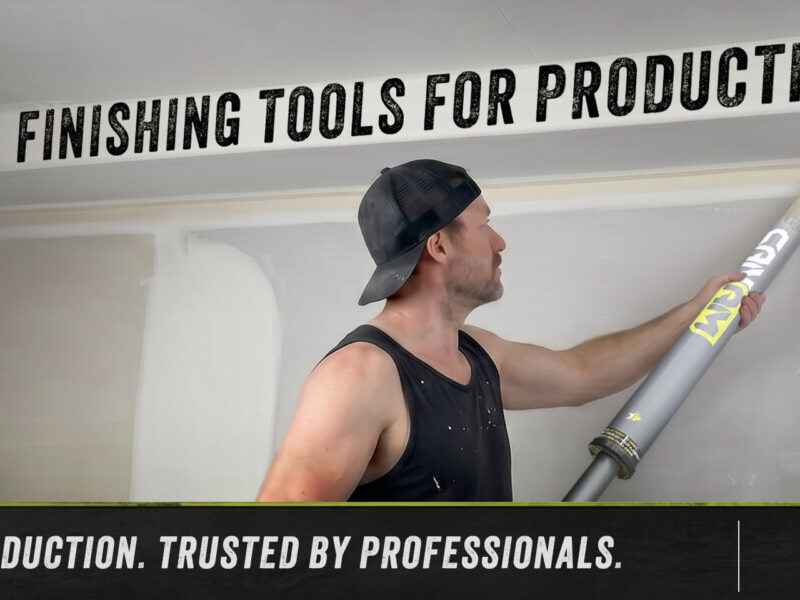 Professional drywall finisher using a CanAm inside corner applicator on a ceiling angle during a production job