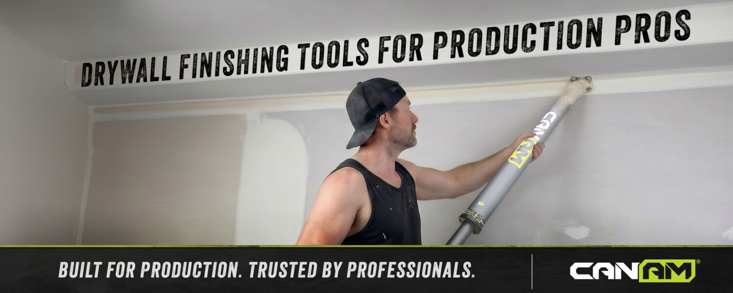 Professional drywall finisher using a CanAm inside corner applicator on a ceiling angle during a production job